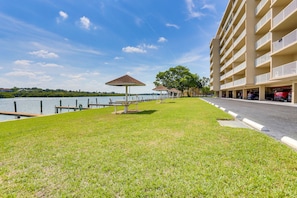 A waterfront hotel with a grassy area, a gazebo, and a parking garage.