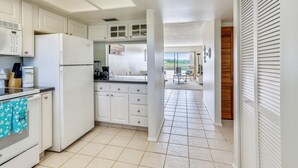 A kitchen with white cabinets, a refrigerator, and a tiled floor.