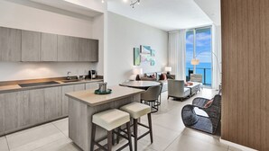 A modern kitchen with a central island, bar stools, and a dining area with a round table and chairs. - Amazing Apartments at Lyfe Resort and Residences (Hollywood)