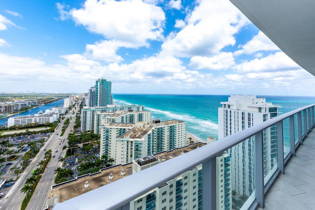 A high-rise building with a view of the ocean and a busy road below.