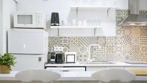 Una cocina moderna con electrodomésticos blancos, salpicadero con diseño y armarios blancos.
