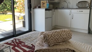 A kitchen with white cabinets, a microwave, and a sink. There is a towel on the floor and a picture frame on the counter. - Studio Meublé 2 Personnes (Castelmaurou)