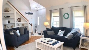 A living room with two dark blue sofas, a white coffee table, and a wooden floor.