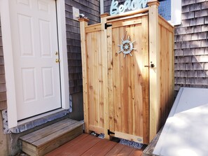 A wooden outdoor storage cabinet with a ship's wheel design, a white door, and a 'Beach' sign above it. - Close to Bass River and Follins Pond With Water Access (2232) (South Yarmouth)