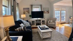 A living room with a sofa, coffee table, TV, and artwork on the wall.
