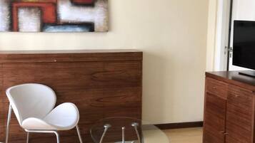 Una habitación moderna con un armario de madera, una mesa de vidrio y una silla blanca.