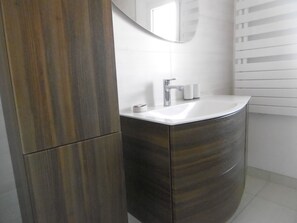 Ein Badezimmer mit einem weißen Waschbecken, einem Spiegel und einem Handtuchspender.