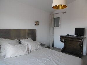 Ein Schlafzimmer mit einem Bett, einem Nachttisch mit Fernseher und einer modernen Lampe.