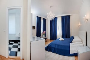 Relax in a serene space with a large bed, glass desk, and stylish chandelier.