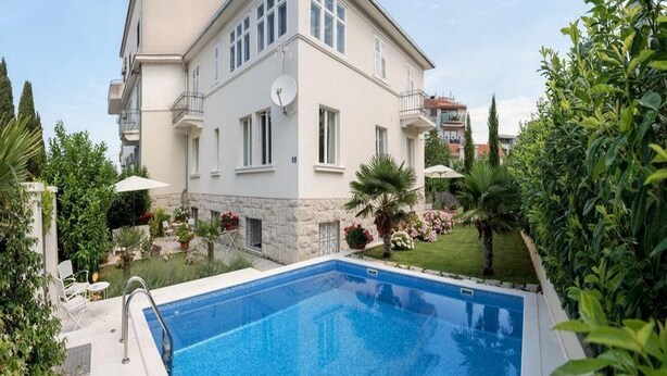 A two-story building with a swimming pool, surrounded by greenery and a well-maintained garden. - Jagoda Apartman (Split)