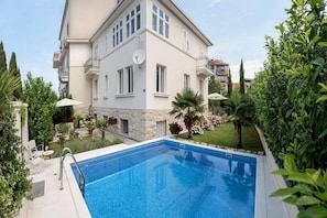 Guests can enjoy a refreshing swim in the pool surrounded by lush greenery and a patio area with outdoor seating.