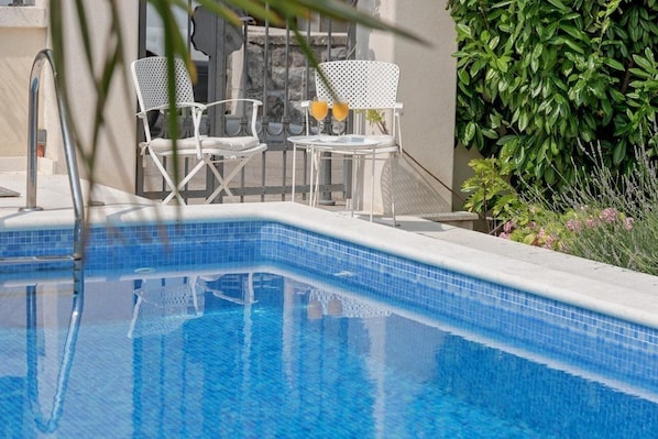 Relax by the pool surrounded by lush greenery and comfortable seating.