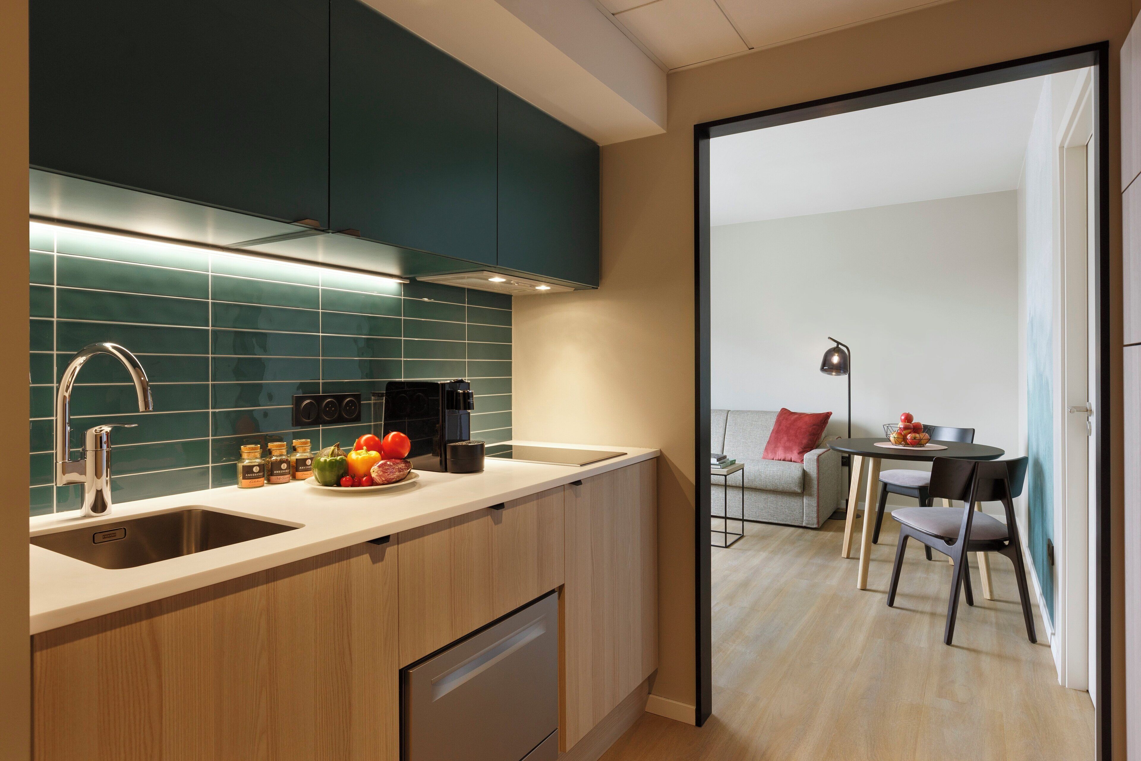 A modern kitchen with a built-in oven, a coffee machine, and a sink.