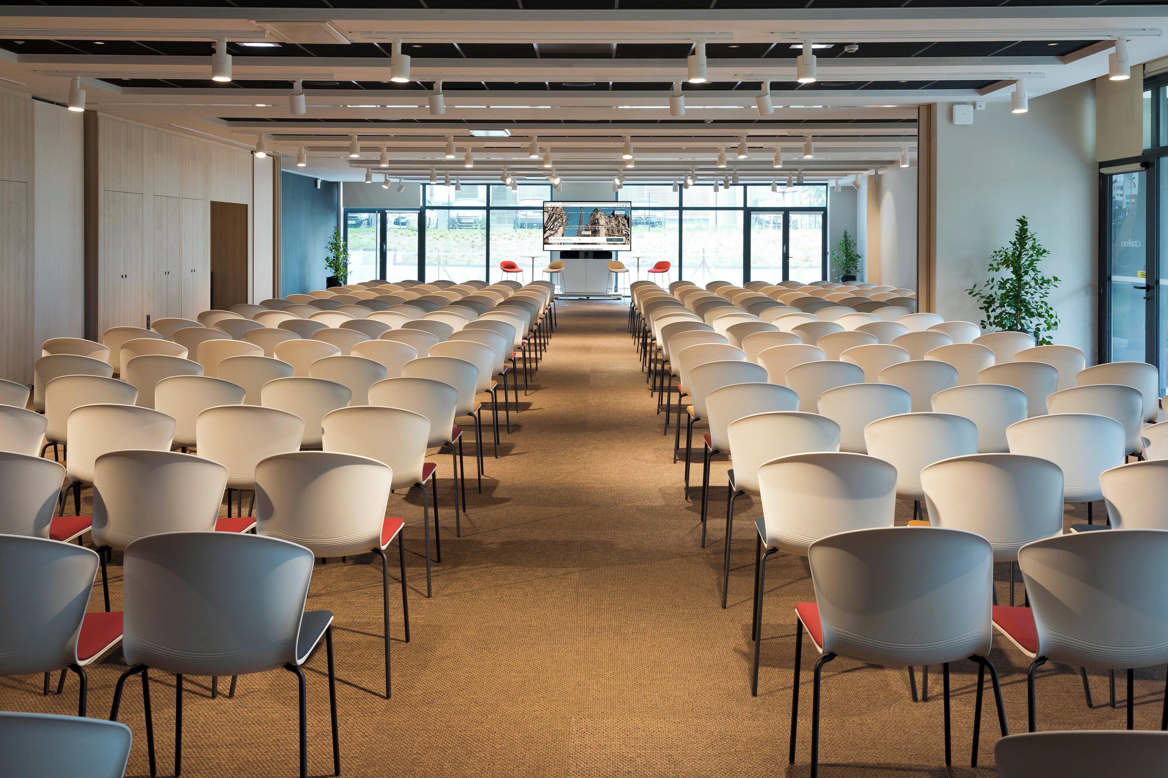 A conference room with rows of chairs, a podium, and large windows.