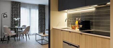 Una cocina moderna con lavavajillas, un fregadero y una cafetera. Hay un comedor con una mesa y sillas.