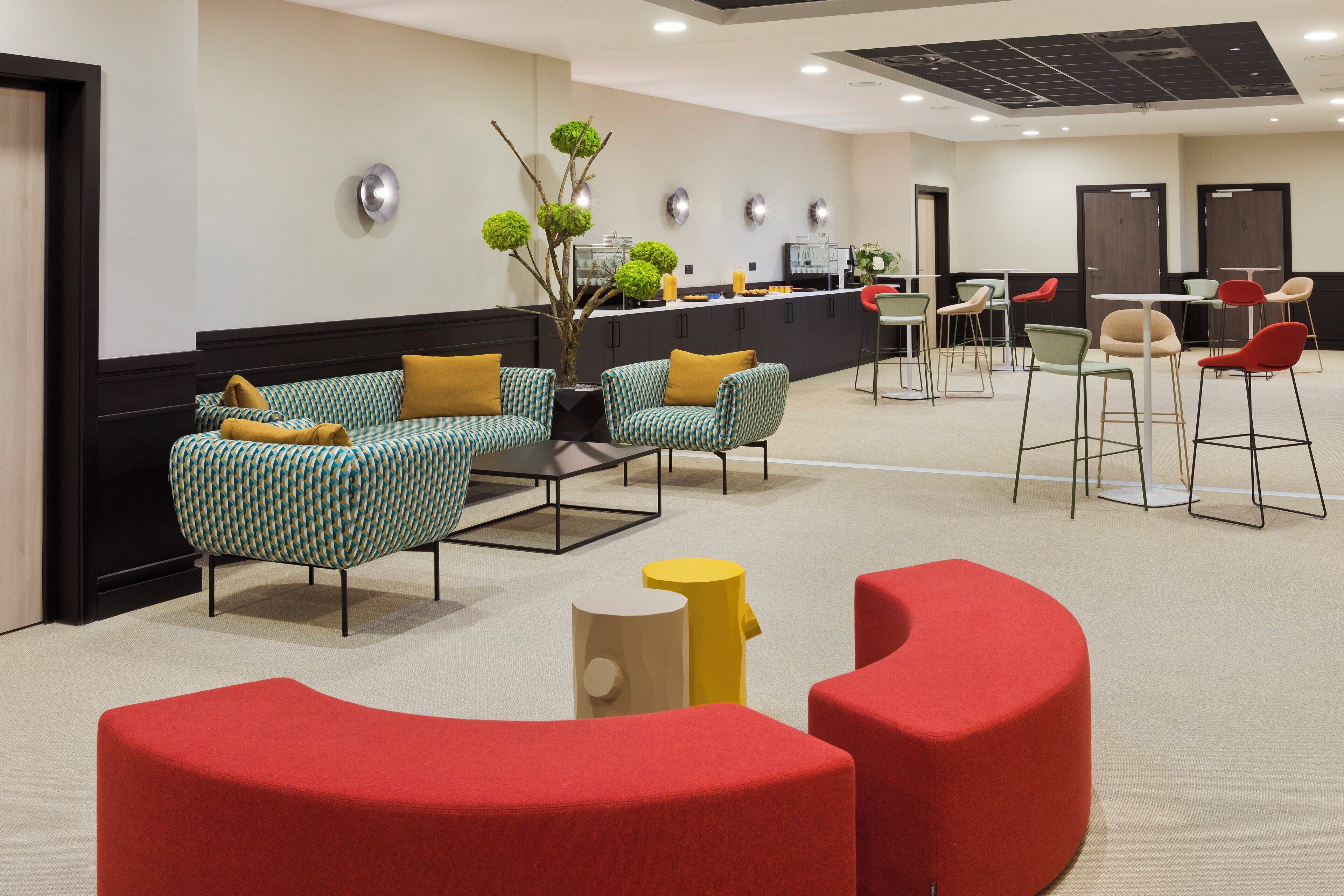 A modern lobby with a reception desk, seating area with patterned chairs, and a bar.