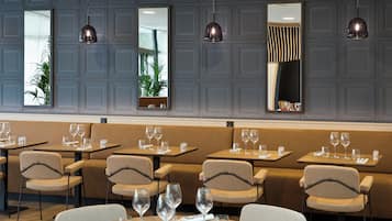 A restaurant interior with booths, tables, and hanging pendant lights.