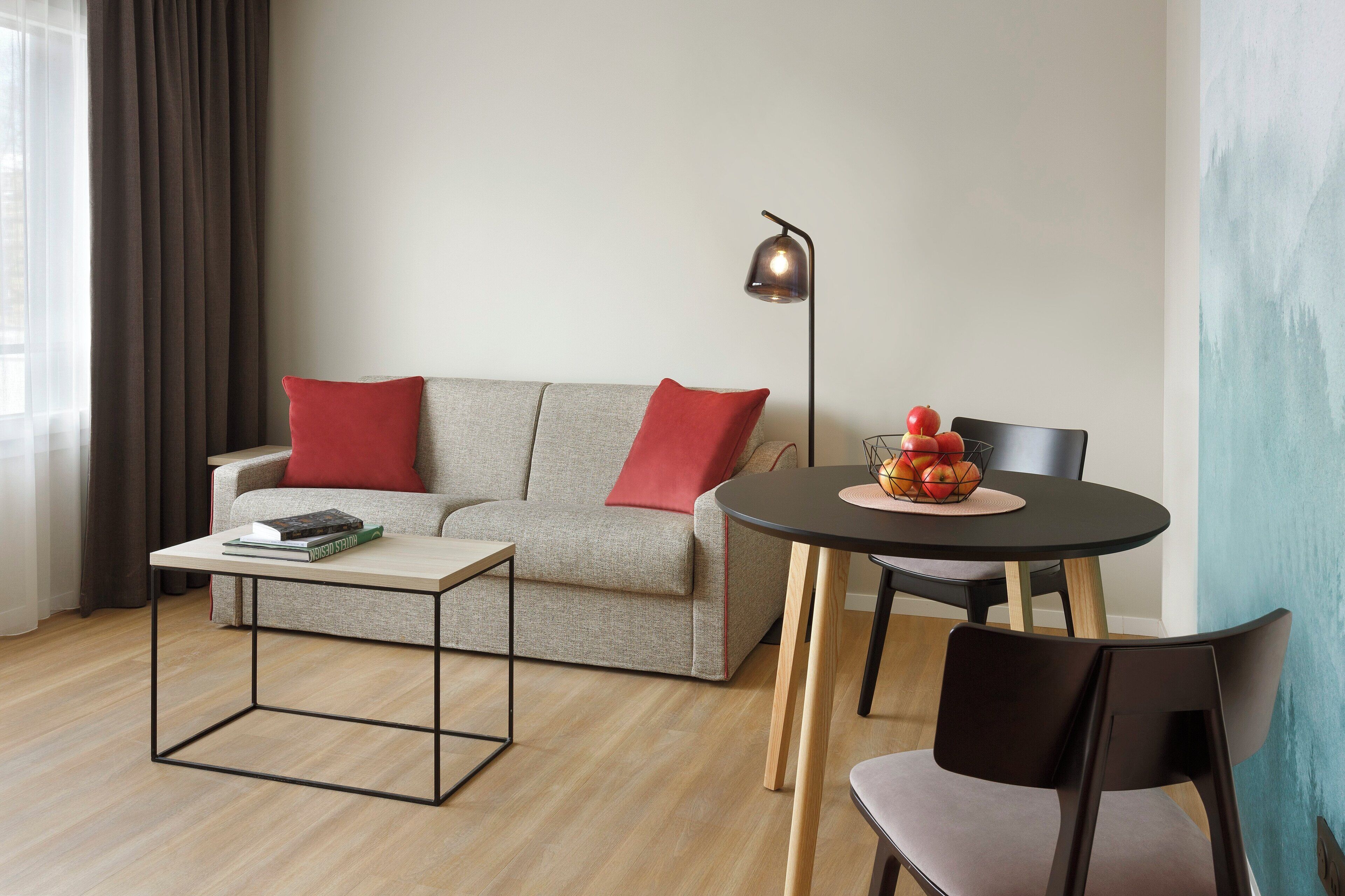 Una sala de estar moderna con sofá, una mesa de centro, una mesa de comedor con sillas y una lámpara de pie.
