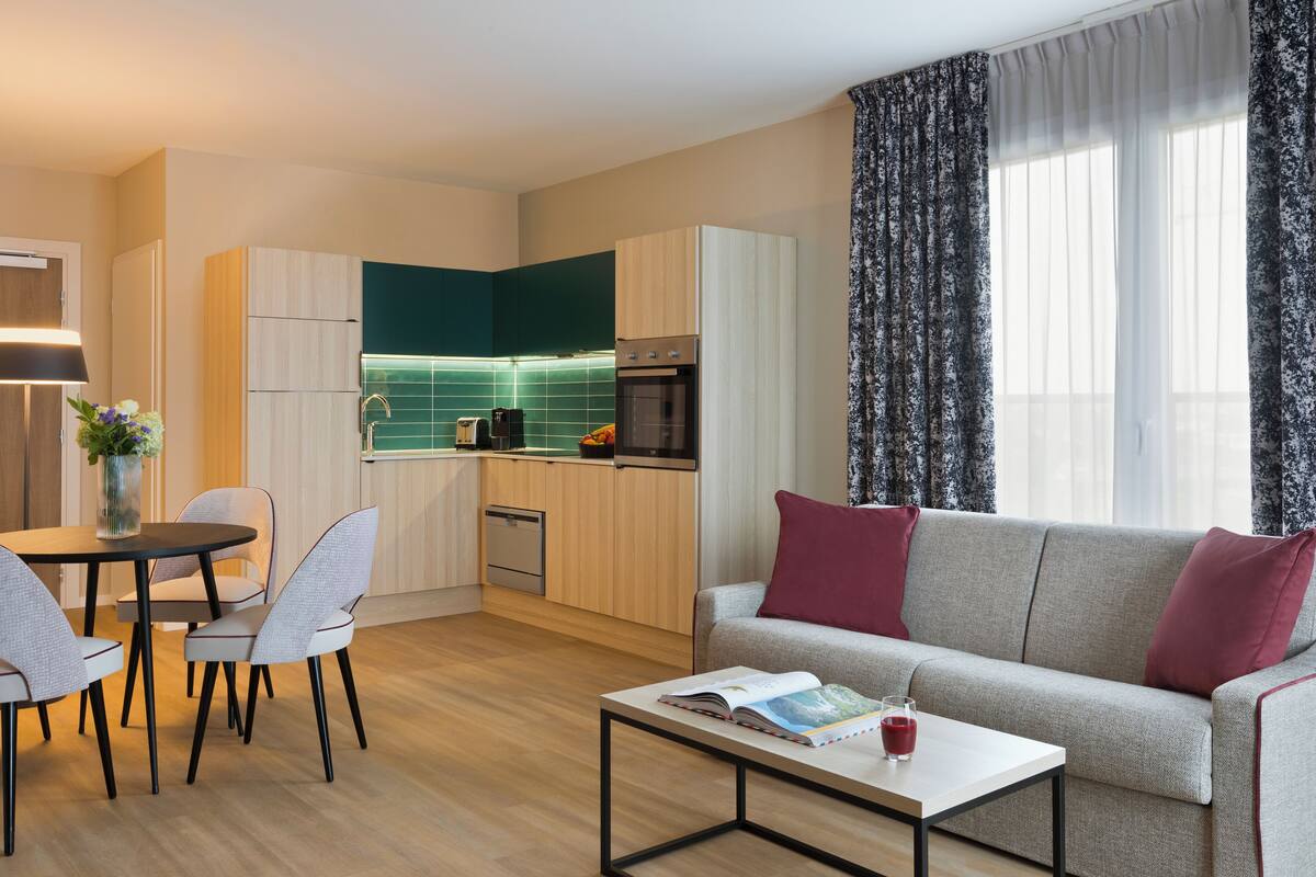 A compact living space with a kitchenette, a dining area, and a sofa with cushions.