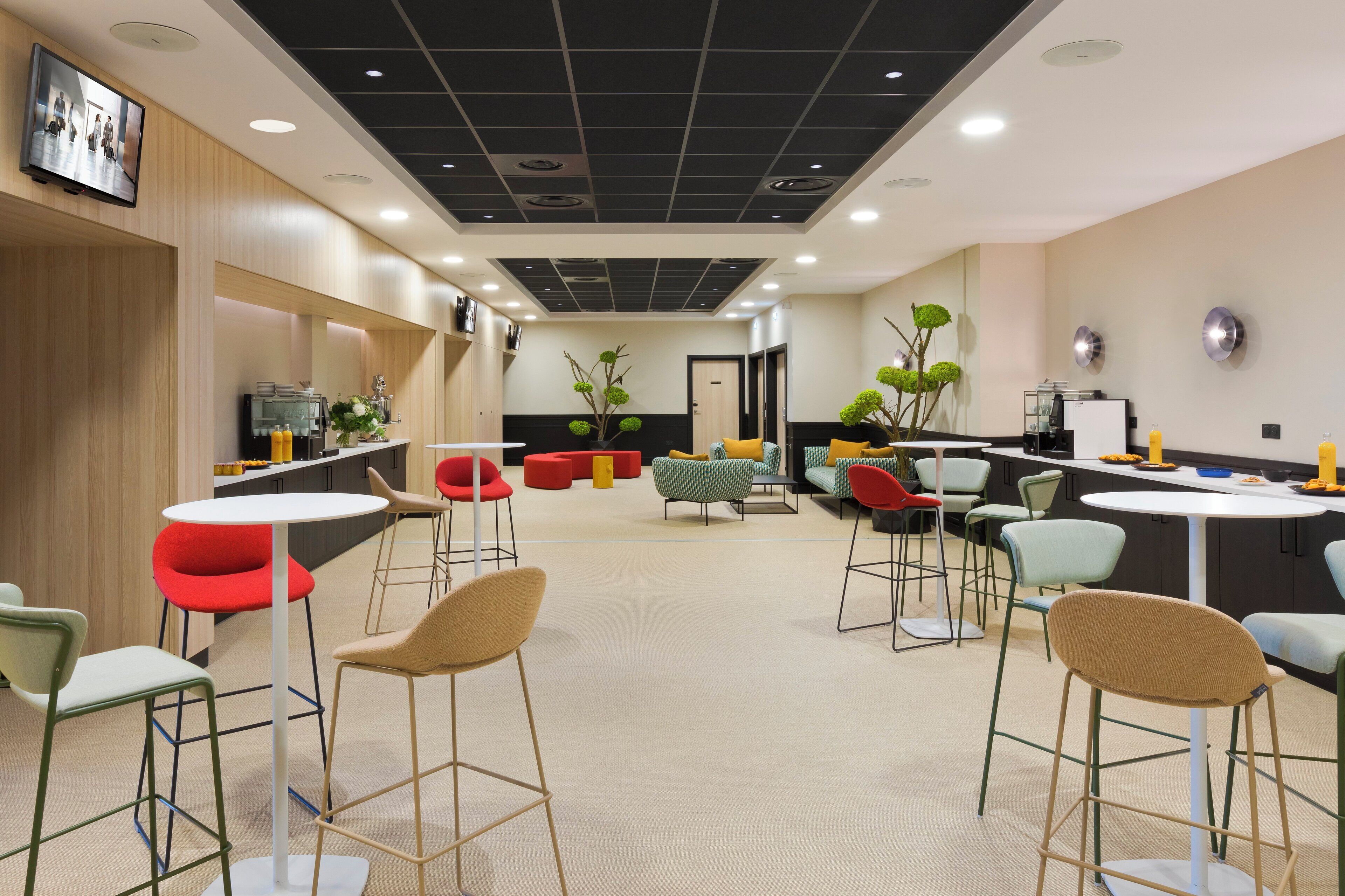 A modern interior with a kitchen area, seating arrangements, and decorative plants.