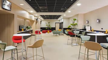 A modern interior with a kitchen area, seating arrangements, and decorative plants.