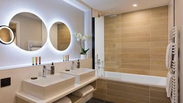 A modern bathroom with two sinks, a large mirror, and a shower.