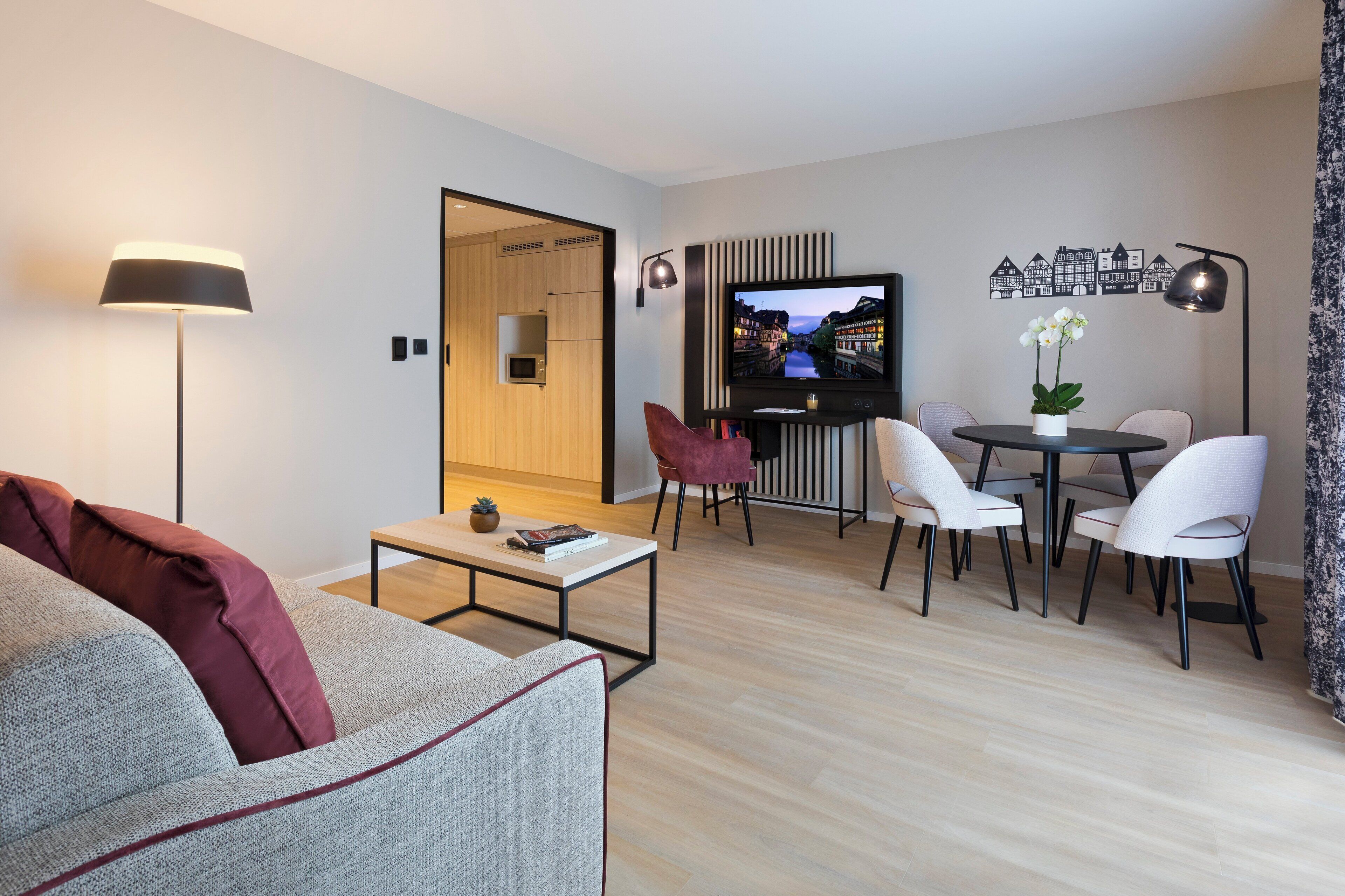 A modern living room with a sofa, coffee table, TV, and dining area with chairs and a table.