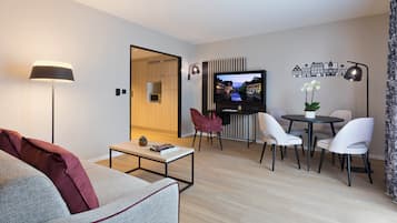 A modern living room with a sofa, coffee table, TV, and dining area with chairs and a table.