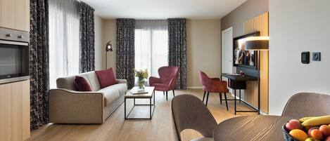 Ein modernes Wohnzimmer mit einer Couch, Sesseln, einem Couchtisch und einem Essbereich mit Tisch und Stühlen.