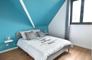 Cozy loft-style room with a bed, bedside tables, and a window offering a view of the outdoors.