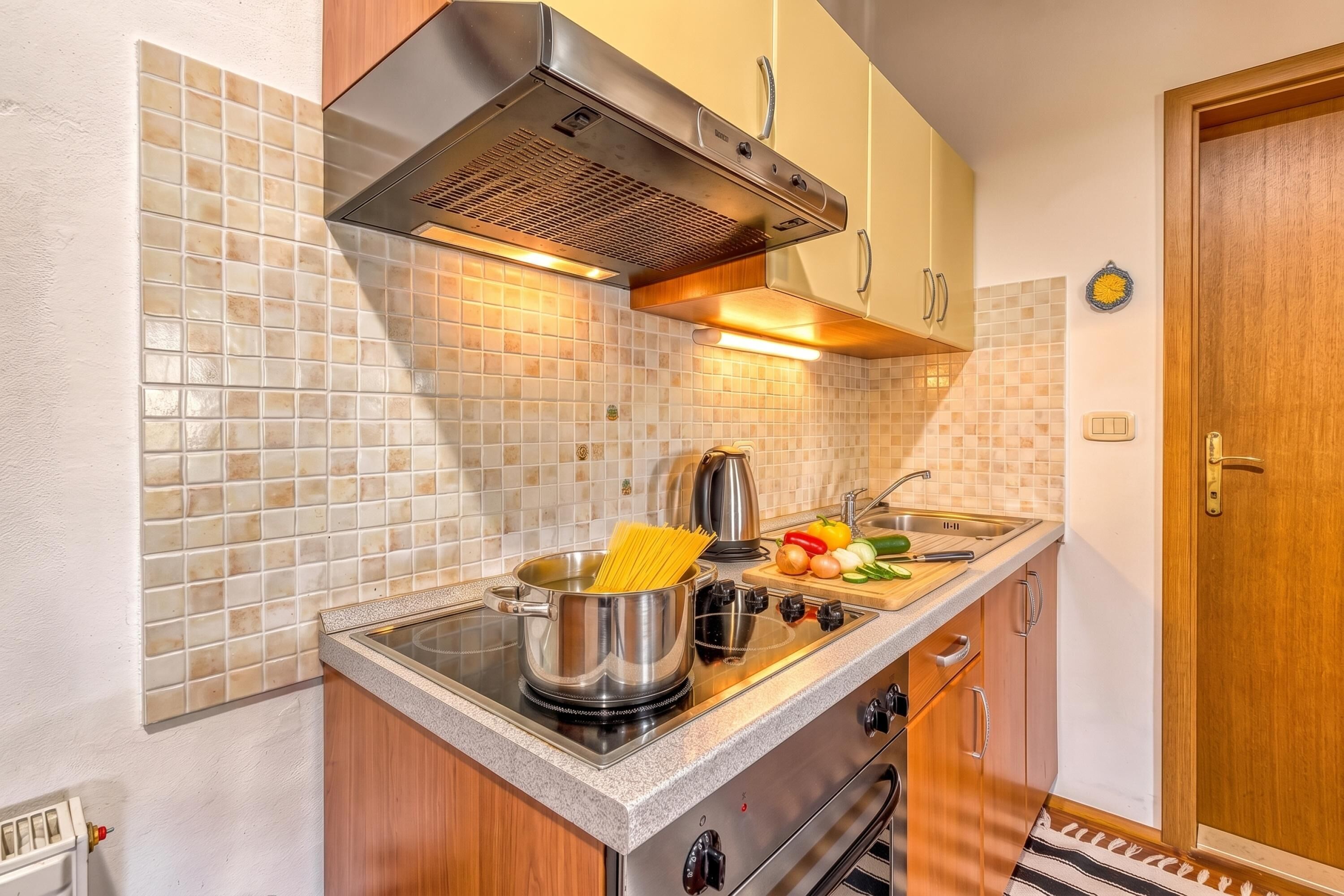 A compact kitchen with a stove, sink, and a tiled backsplash.