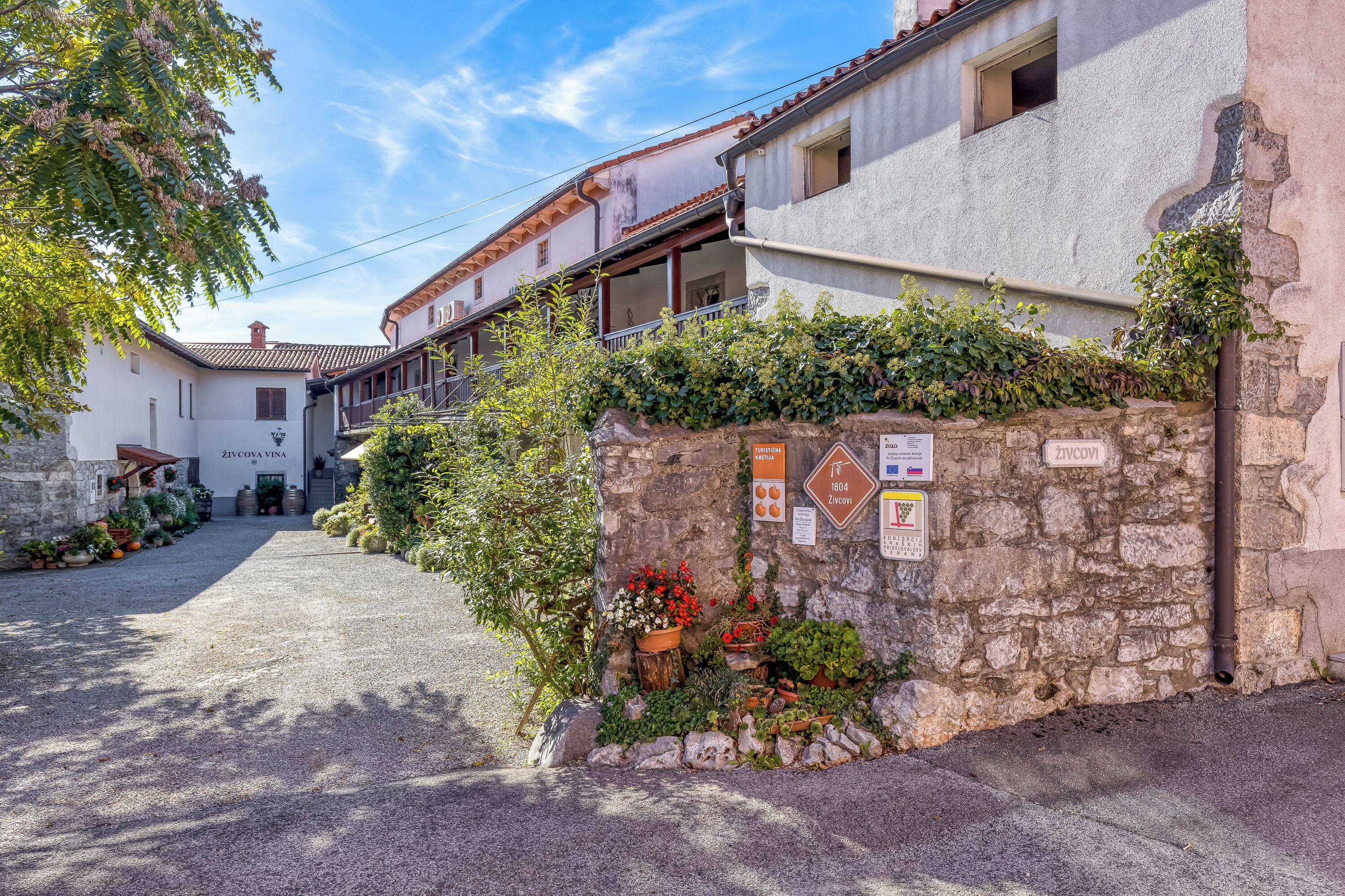 A narrow street with traditional stone buildings, a cobblestone path, and a stone wall with signs.