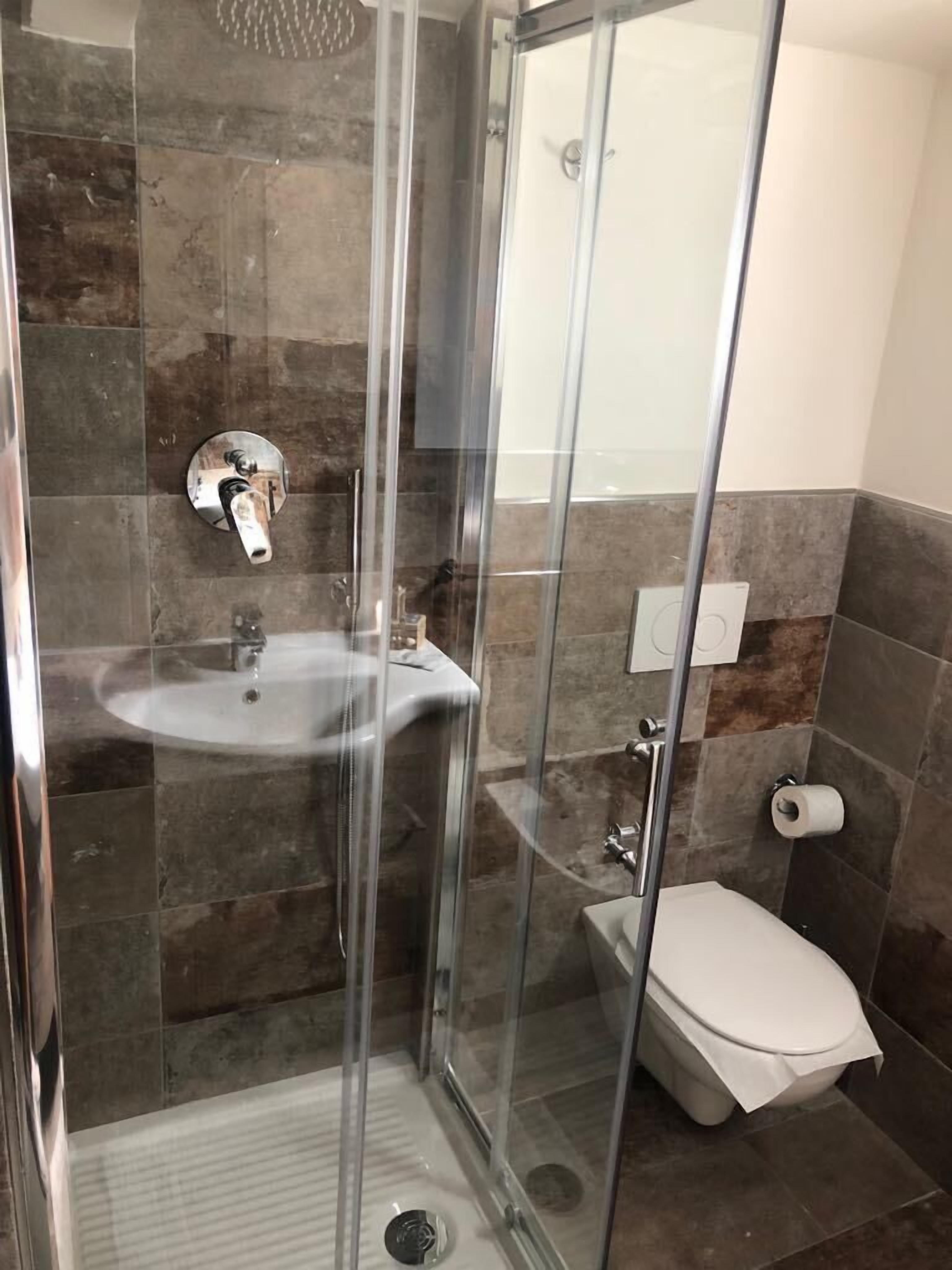 Ein modernes Badezimmer mit einer Glasdusche, einem Waschbecken und einer Toilette.