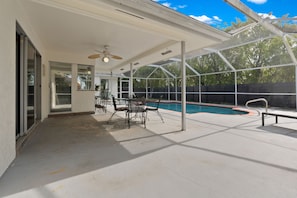 A covered patio area with a pool, outdoor furniture, and a ceiling fan. - Family Home w/Pool , On Golf Course & Near Beach !  (Fort Myers)