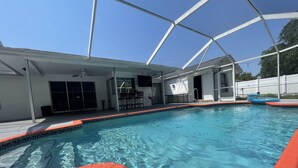 A swimming pool with clear blue water, surrounded by a covered area with a white roof and a white fence in the background. - Family Home w/Pool , On Golf Course & Near Beach !  (Fort Myers)