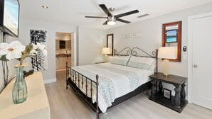 A bedroom with a bed, bedside tables, a ceiling fan, a TV, and a view of the kitchen. - Family Home w/Pool , On Golf Course & Near Beach !  (Fort Myers)