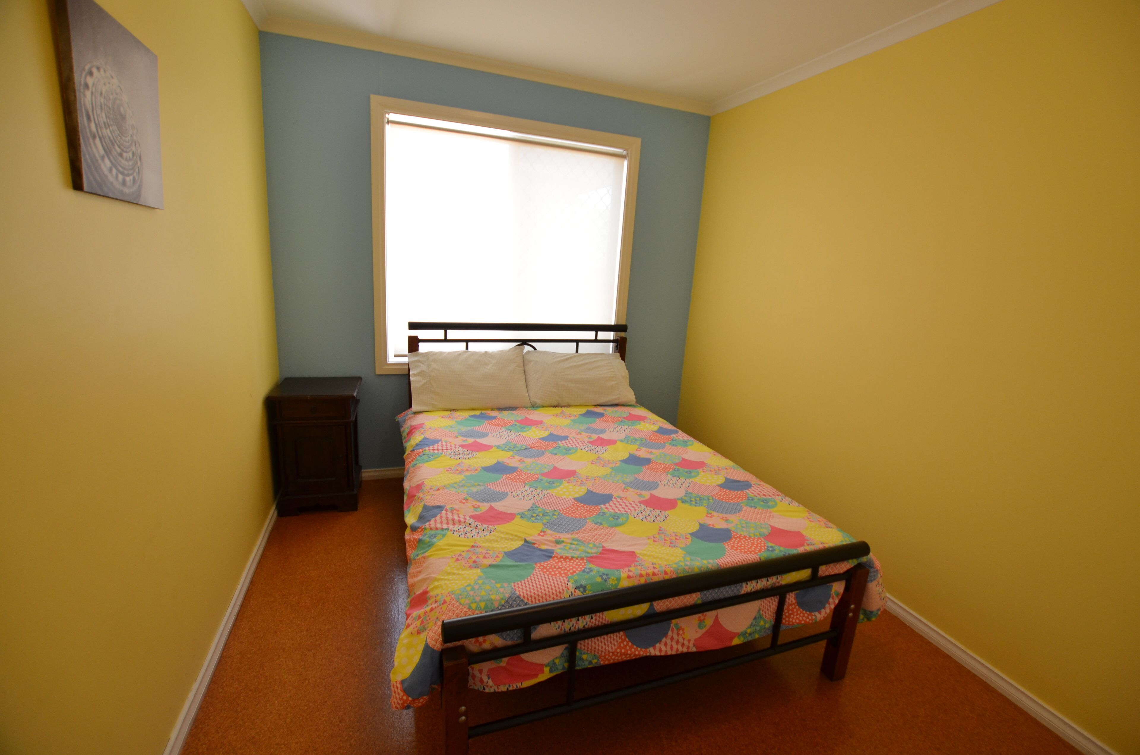 Ein Schlafzimmer mit Bett, Nachttisch und Fenster.