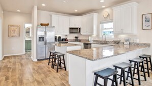 A modern kitchen with white cabinets, granite countertops, and stainless steel appliances. - Steps to Beach | Pet Friendly | Community Pools and Pier (Gulf Shores)