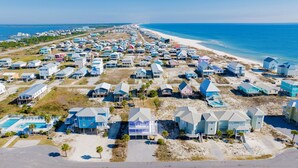 A coastal residential area with houses on stilts, a beach, and a clear view of the ocean. - Steps to Beach | Pet Friendly | Community Pools and Pier (Gulf Shores)