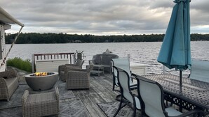 A deck with wicker furniture, a fire pit, and a view of a lake.