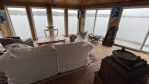 Interior de una cabaña con sofá, una mesa y vistas a un lago.