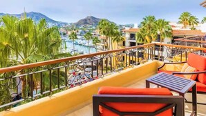 A balcony with a view of a marina, palm trees, and a mountain in the distance. - Two (2) Superb Studios in Cabo (Cabo San Lucas)