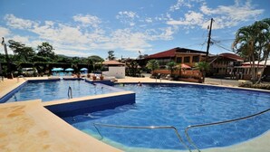 Ein Swimmingpool mit klarem, blauem Wasser, umgeben von Liegestühlen und Sonnenschirmen.