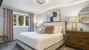 Un dormitorio con cama, cómoda, cortinas en la ventana y un cuadro en la pared.