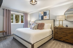 A bedroom with a bed, a dresser, a window with curtains, and a painting on the wall. - Ski Condo in Vail Village (Vail)