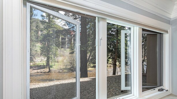 Una habitación con ventanas amplias, una mesa de madera y una planta en maceta.