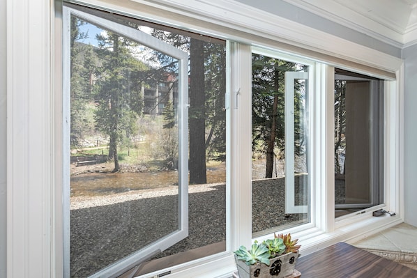 Una habitación con ventanas amplias, una mesa de madera y una planta en maceta.