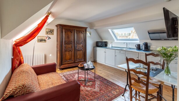 Un appartement-loft confortable avec un coin repas, une cuisine et un canapé rouge.