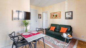 A compact living space with a dining area, a sofa, and a TV mounted on the wall.