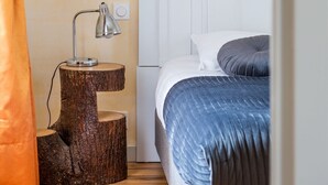 A bedroom with a bed, a nightstand with a lamp, and a wooden tree stump.